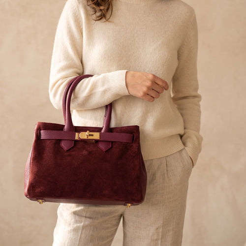 una donna che tiene in mano una borsa di camoscio